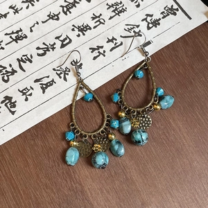 Detail of vintage bohemian drop earrings with turquoise marble texture and bronze finish