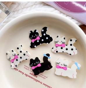 Detailed view of polka dot cat hair clips set with pink bows on a ceramic tray
