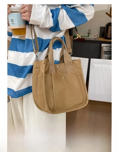 Detail of khaki canvas tote bag featuring side pockets with metal rivets and shoulder strap