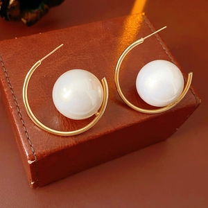 Detailed view of French vintage gold C-shape hoop earrings with white pearls on leather