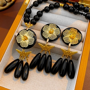 Detail of vintage flower and butterfly necklace set with black agate beads in a jewelry box