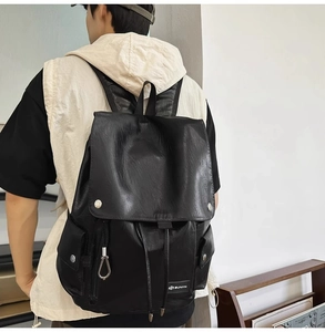 Dettaglio dello zaino in pelle nera con doppie tasche frontali e fibbie in metallo lucido