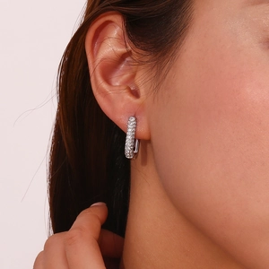 Macro close-up of a silver rectangular hoop earring with micro-pave clear gemstones on a model