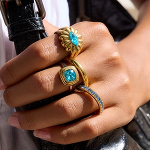 Three-piece gold titanium steel ring set with blue zircon gemstones on a hand