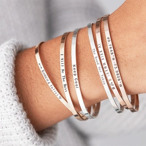 Close-up of customized silver and rose gold open cuffs with personalized engravings