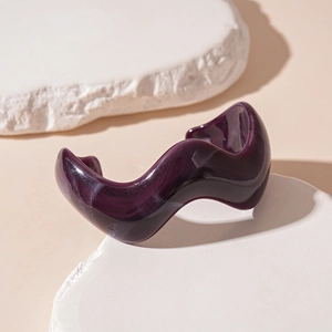 Macro shot of wavy purple acrylic bangle with marble texture on stone display stands