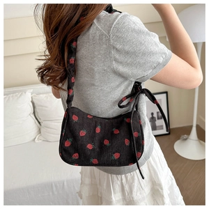Black corduroy shoulder bag with strawberry embroidery and bow detail on female model