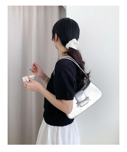 Detailansicht einer silbernen Metallic-Schultertasche mit dekorativer Schleife vorne