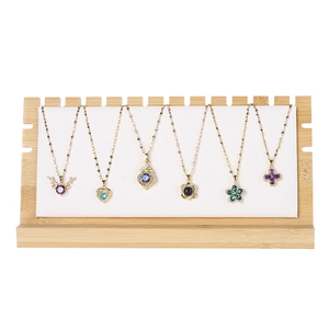 Bamboo necklace display stand with white velvet backboard holding six gemstone pendants
