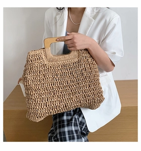 Detailed view of handmade woven straw tote bag with smooth round wooden handles
