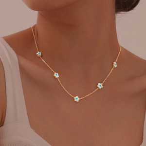 Close-up of a gold choker featuring five blue evil eye petal charms on a female model neck
