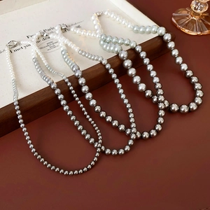 Flat lay of gradient pearl necklaces showing transition from white to dark grey finish