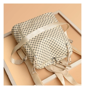 Detail view of beige backpack with black polka dots, multiple zippers and adjustable straps