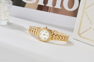Detail of gold square watch with Roman numerals, crystal bezel, and blue gem crown