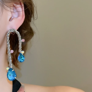 Dettaglio orecchini intrecciati argento con cristallo a goccia blu e pietre rosa su modella