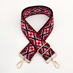 Close-up of ethnic jacquard guitar strap with golden metal clasps and woven pattern