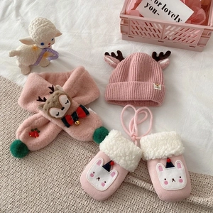 Detailed view of pink knitted baby hat with reindeer antlers and fuzzy scarf with gloves