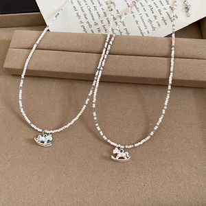 Détail de colliers perlés avec cristaux colorés et pendentifs poney en émail doux