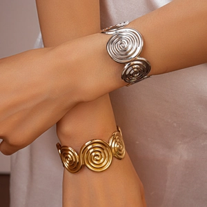 Detailed view of gold and silver spiral open bangles on a model's arm for luxury style