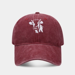 Close-up of vintage washed burgundy baseball cap featuring detailed white cow embroidery