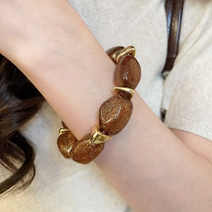 Close-up of brown acrylic oval beaded bracelet with gold metallic spacers on a wrist