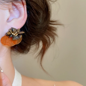 Close-up of retro shell and tiger eye earrings worn on model's ear in soft light