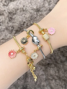 Close-up of layered gold and silver snake chains with colorful enamel daisy charms