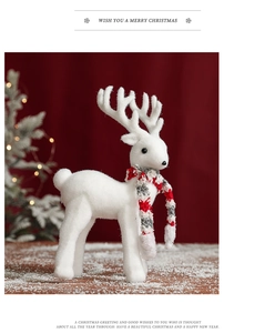 Detailed view of a white flocked deer ornament with a red and grey scarf on snow