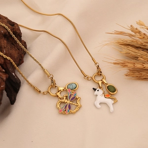 Golden dragonfly and unicorn necklaces with colorful enamel details on rustic wood background