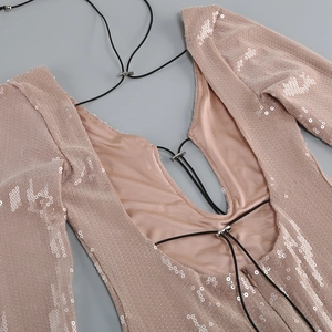 Detalle de vestido rosa con lentejuelas, escote en V profundo y cordón negro ajustable