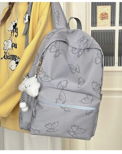 Detailed view of gray butterfly pattern backpack with cute cloud charm on a model