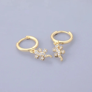 Detail view of gold gecko earrings with white zircon accents on a neutral backdrop