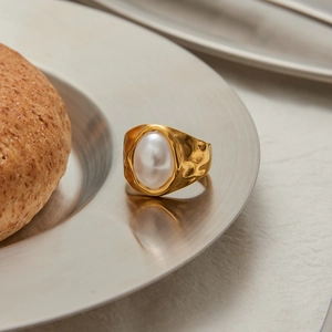 Artistic shot of a gold hammered titanium ring featuring a large oval imitation pearl