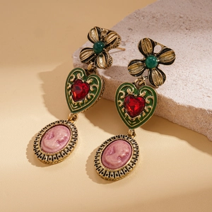 Vintage bronze earrings with flower, red heart, and pink cameo portrait on a stone base