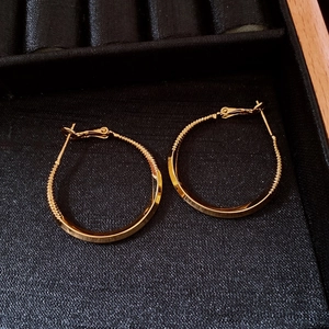 Macro shot of 18k gold plated hoop earrings with twist texture on black velvet tray