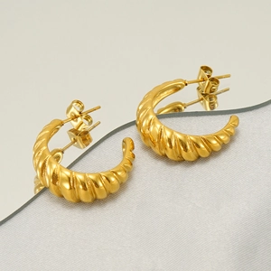 Macro detail of golden spiral geometric earrings with polished finish on reflective mirror