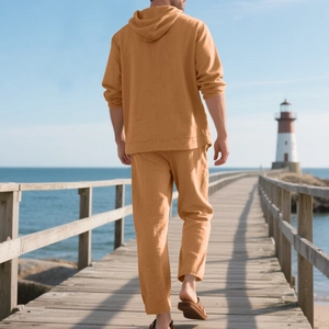 Men's loose linen hooded shirt and pants set shown in an outdoor beach walk perspective