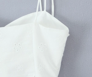 Detailed view of white floral lace embroidery on camisole top with thin shoulder straps