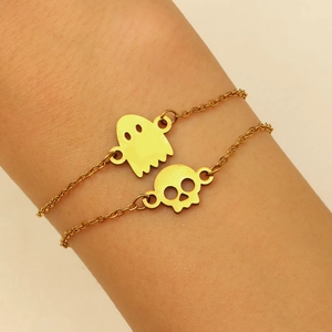 Golden stainless steel bracelet with ghost and skull charms on woman wrist