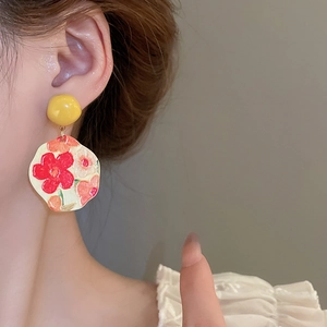 Detail shot of French sunflower earrings with artistic floral pendants on model