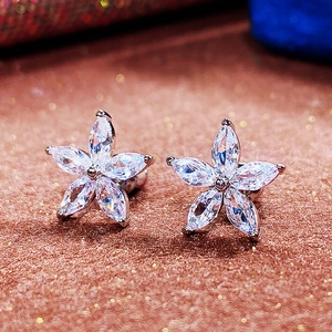 Sparkling five-petal flower stud earrings with marquise-cut cubic zirconia on velvet background