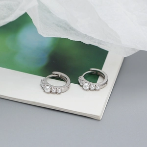 Macro shot of silver S925 earrings with white pearls displayed on a white card