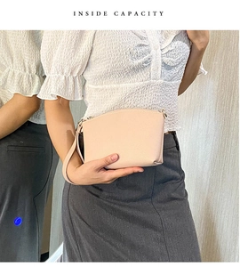 Detail showing the internal capacity of the pink leather clutch held by a model