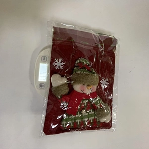 Close-up of a Christmas knitted gift bag with a 3D snowman doll and a green knit scarf