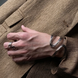 Close-up of a silver twisted multi-layer metal bracelet worn with a brown blazer