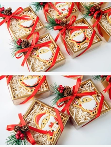 Close-up of Santa Claus iced cookies in festive gift boxes with pine cones decoration