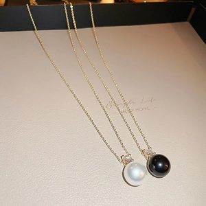 Detailed close-up of white and black pearl necklaces with gold chain and cubic zirconia
