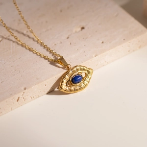 Detailed close-up of an 18K gold evil eye pendant with lapis lazuli on a stone surface