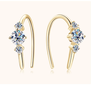 Detail of gold drop earrings featuring three round-cut moissanite stones in prong setting