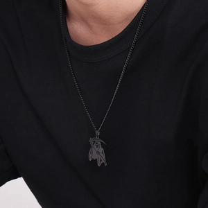 Detail of a black grim reaper scythe pendant necklace on a model wearing a black t-shirt